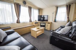 a living room with two couches and a television at 6 Berth Caravan With Decking At Kessingland Beach In Suffolk Ref 90045sg in Benacre