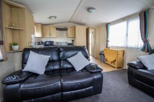 een woonkamer met een leren bank in een caravan bij 6 Berth Caravan With Decking At Kessingland Beach In Suffolk Ref 90045sg in Benacre