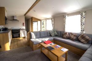 a living room with a couch and a table at Lovely 6 Berth Caravan At Coopers Beach Park In Essex Ref 49075p in East Mersea