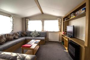 a living room with a couch and a tv at Lovely 6 Berth Caravan At Coopers Beach Park In Essex Ref 49075p in East Mersea