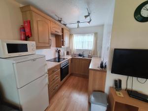 a kitchen with wooden cabinets and a white refrigerator at Lovely 5 Berth Chalet In Hemsby Nearby Great Yarmouth Ref 73034c in Hemsby