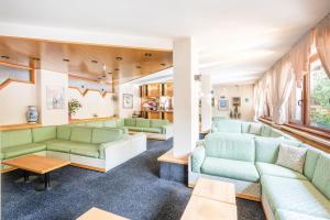 ein Wohnzimmer mit grünen Sofas und Tischen in der Unterkunft Hotel Alpina in Madonna di Campiglio