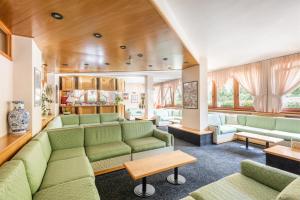 a living room with green couches and tables at Hotel Alpina in Madonna di Campiglio