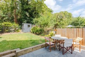 a patio with a table and chairs in a backyard at Modern 3 Bedroom Home in Honor Oak beside Nature Reserve in London