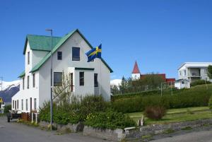 ein weißes Haus mit einer Flagge davor in der Unterkunft Ásgarður in Hrísey