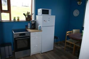 a kitchen with a white refrigerator and a microwave at Ásgarður in Hrísey
