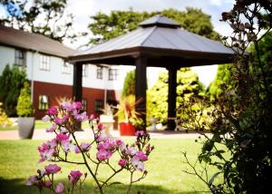 a gazebo in a yard with pink flowers at Beaufort Park Hotel in Mold