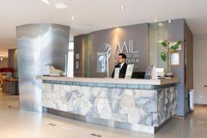 Un hombre de pie detrás de un mostrador en un vestíbulo. en Lagos Andinos, en San Carlos de Bariloche