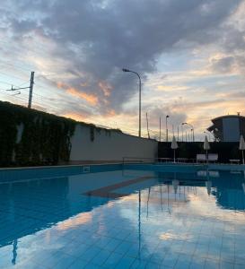 a large swimming pool with a sunset in the background at Hotel Royal in San Benedetto del Tronto