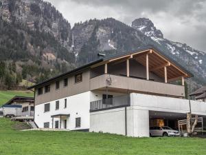 a building with a car parked in front of a mountain at Burtscherhof in Braz in Ausserbraz