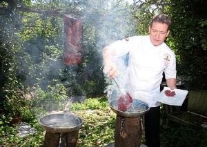 Een man kookt vlees in een grill. bij Saints Bay Hotel in St Martin Guernsey