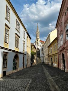 una calle vacía en un viejo pueblo con una torre de reloj en Varga Apartman en Sopron
