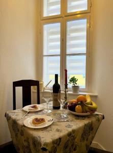 una mesa con una bandeja de fruta y una botella de vino en Varga Apartman en Sopron