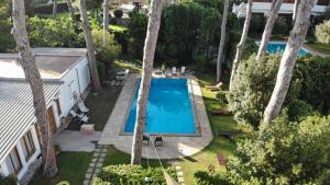 einen Blick über einen Pool in einem Garten mit Bäumen in der Unterkunft BUBA BnB SUPERIOR in Anzio