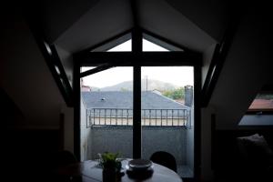 - une fenêtre dans une chambre avec une table et un balcon dans l'établissement Fabulos Ático con vistas al Monasterio, à San Lorenzo de El Escorial