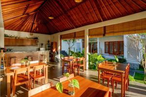 un restaurant avec des tables et des chaises en bois dans l'établissement Eden Guest House Canggu, à Canggu