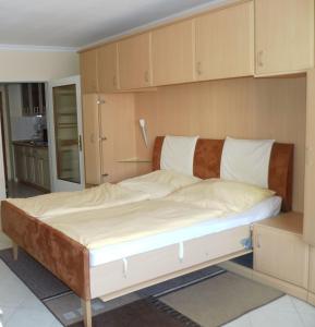 Bett in einem Zimmer mit Holzschränken in der Unterkunft 13-36, sehr Strandnah, im Herzen Westerlands, Westbalkon, 1 Zi in Westerland