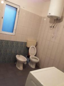 a bathroom with a toilet and a sink and a window at House 28 in Orikum +3 photos