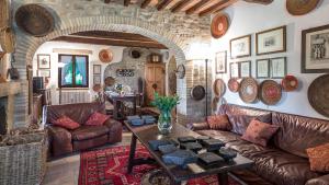 sala de estar con muebles de cuero y pared de piedra. en VILLA DUE VIGNE 8, Emma Villas, en Monte Castello di Vibio