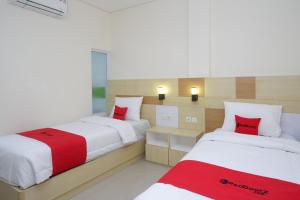 duas camas num quarto com vermelho e branco em RedDoorz Plus near Pasar Gede Solo em Surakarta