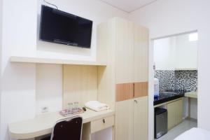 a kitchen with a desk with a tv on a wall at RedDoorz Plus near Pasar Gede Solo in Solo