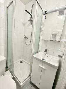 a white bathroom with a shower and a sink at Studio Bonne Nouvelle in Paris