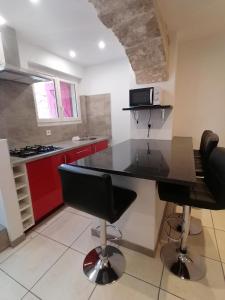 a kitchen with a black counter and red cabinets at Appartement paisible entre terre et mer in Cabrières