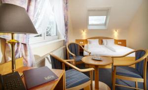 プラハにあるPension Kernのベッド、テーブル、椅子が備わるホテルルームです。