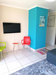 ein Wohnzimmer mit 2 Stühlen und einem Flachbild-TV in der Unterkunft Muizenberg Mountain View Apartment in Kapstadt