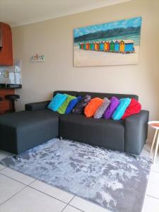 eine schwarze Couch mit bunten Kissen drauf in der Unterkunft Muizenberg Mountain View Apartment in Kapstadt