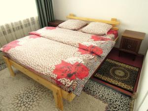 a bedroom with two twin beds with red flowers on them at Arthouse in Karakol