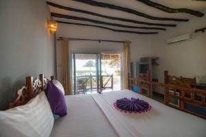 a bedroom with a large white bed with a purple flower on it at Tanzanite Beach Resort in Nungwi
