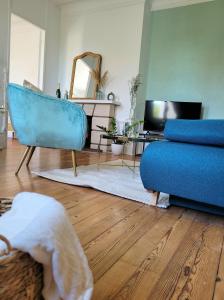 a living room with a blue couch and a tv at LA PARENTHÈSE HAVRAISE - Parking privé Plein centre & Très calme in Le Havre