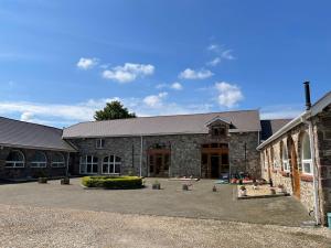 a large stone building with a courtyard in front of it at Red Kite Barn in Ammanford