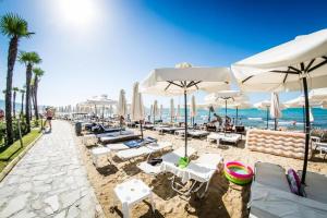 una spiaggia con ombrelloni e sedie bianchi e l'oceano di Privilege Fort beach Apartman Sveti Vlas 61m2 a Elenite
