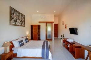 une chambre avec un lit et une télévision dans l'établissement Eden Guest House Canggu, à Canggu 15 autres photos