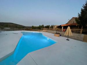 ein blauer Pool mit einem Tisch und einem Sonnenschirm in der Unterkunft LA RATONERA in Podentes