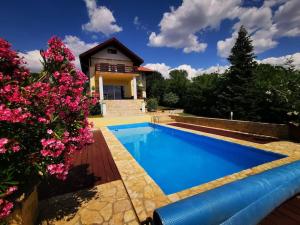 a swimming pool in front of a house with flowers at Villa Somlyó in Fót