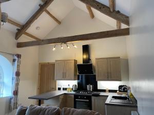a kitchen with wooden cabinets and a stove top oven at Red Kite Barn in Ammanford