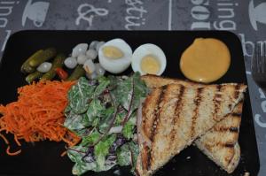 un plato negro con un sándwich y huevos y verduras en Bon séjour, en Theux