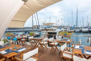 een terras met tafels en stoelen en boten in een jachthaven bij Locanda da Toto in Genua