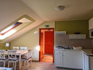 a kitchen with a table and chairs and a red door at Palantír Panzió in Miskolc