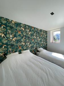 a bedroom with two beds with a floral wallpaper at Gîte Les 27 in Saint-Denis-le-Ferment