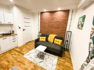 a living room with a black couch and a brick wall at Leśne Zacisze Iwkowa in Iwkowa