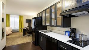 a kitchen with a sink and a room with a bed at Candlewood Suites Carrollton, an IHG Hotel in Carrollton
