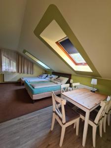 ein Schlafzimmer mit einem Bett, einem Tisch, einem Bett und einem Fenster in der Unterkunft Palantír Panzió in Miskolc