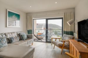 a living room with a couch and a flat screen tv at 6 Woolacombe West - Luxury Apartment at Byron Woolacombe, only 4 minute walk to Woolacombe Beach! in Woolacombe