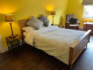 a bedroom with a large bed and two lamps and a chair at St John's Town of Dalry Glentress Apartment 1 in Dalry