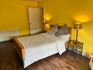 a bedroom with a large bed with yellow walls at St John's Town of Dalry Glentress Apartment 1 in Dalry