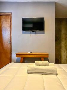 1 dormitorio con 1 cama y TV en la pared en Ariché Valladolid Hotel & Hostal, en Valladolid